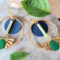 Boucles d'oreilles Ciewenn créoles composées d'un maxi cercle doré décoré d'un jeu de pampilles géométriques dorées vertes et bleues.