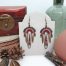 Boucles d’oreilles micro macramé CieWenn rouge écru marron et bronze composées d’un micro macramé rouge, écru, marron et noir tissé autour d’un petit cercle bronze. Il est décoré de jolies perles rouges et bronzes harmonieusement mêlées. Des fines pampilles et une petite chaînette bronze viennent finir l’ensemble.