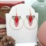 Boucles d’oreilles créoles CieWenn composées d'un maxi cercle doré décoré de perles et d'un jeu de pampilles géométriques dorées et rouges.