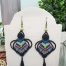 Boucles d'oreilles micro macramé CieWenn composées d'un micro macramé bleu, vert, noir, corail et violet terminé par un fin pompon et parsemé des perles.