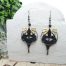 Boucles d'oreilles micro macramé CieWenn composées d'un micro macramé noir parsemé de perles et décoré d’un cercle bronze et de pampilles noires et dorées.